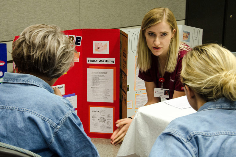 nursing student talking to two women about health issues.