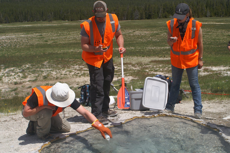 one of three people pours liquid into a volcano pool