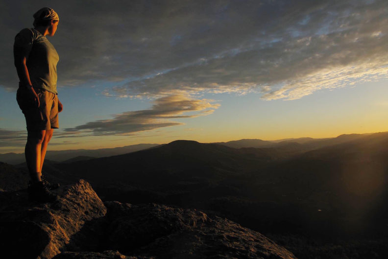 woman overlooking mountains and sunset