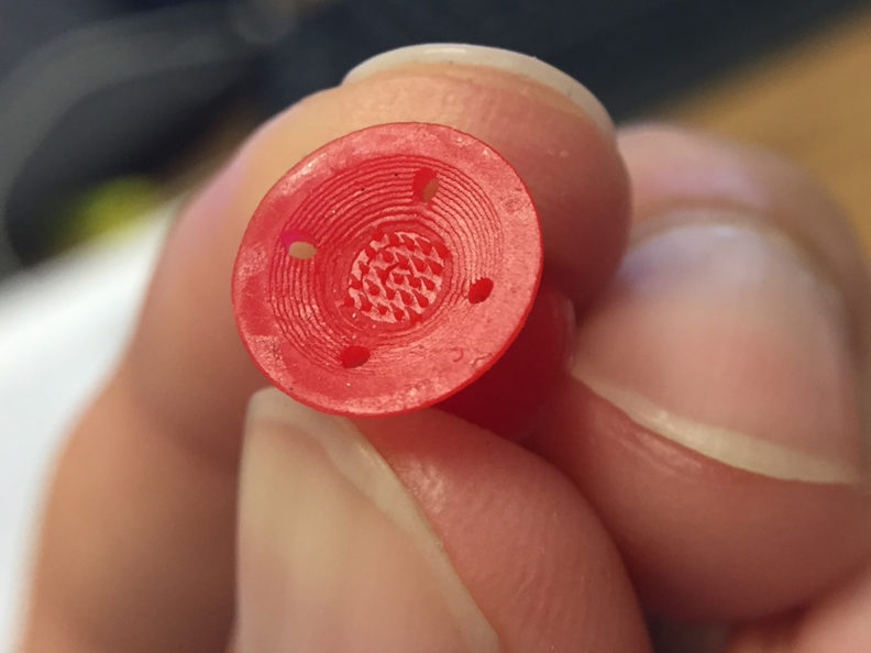 Closeup of fingers holding a red plastic looking disc.
