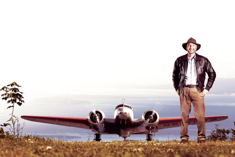 Spink stands in the foreground with WWII era twin-engine plane behind him.