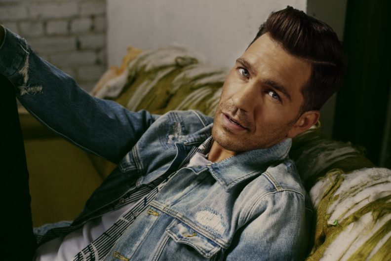 Cloesup of Andy Grammer sitting on couch.