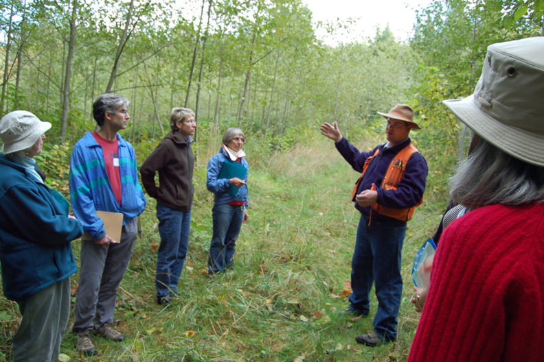 forester talking to group in treed area