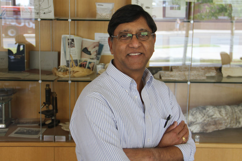 Hanu Pappu stands in front of glass shelf display.