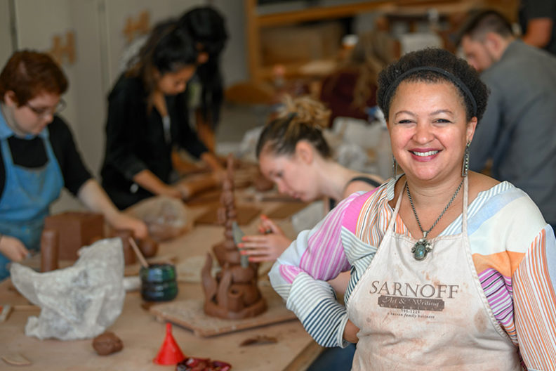 Art teacher with art students at work behind her