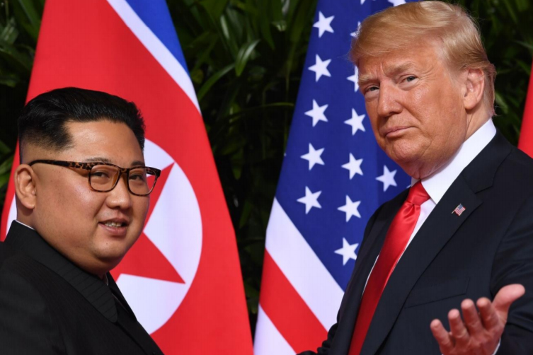 Kim Jong-un and Donald Trump face each other with their nations' flags in background.