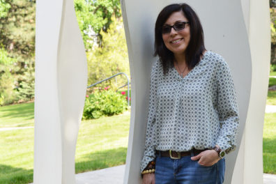 Lugo-Lugo leans against an outdoor sculpture on WSU campus.