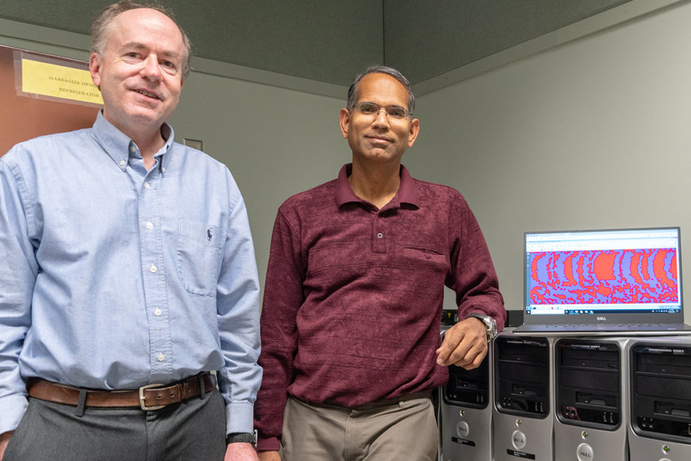 Belzer and Sivakumar stand beside a row of computer servers.