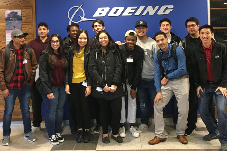 Students gathered in front of wall with Boeing logo.