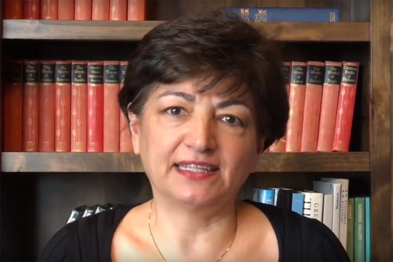 Closeup of Alamdari in front of bookshelf.