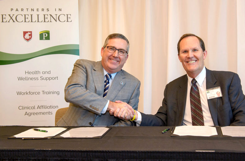 Schulz and Adams shake hands during formal signing.
