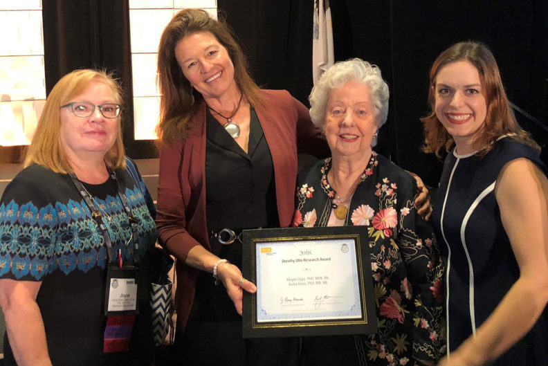 Four women in nursing hold plaque presented at conference.