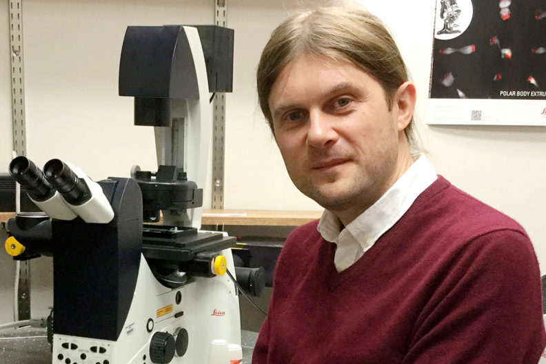 Smertenko in lab by a microscope.