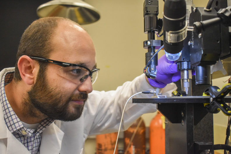 Arda Gozen observing a 3D printer.