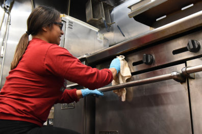 WSU student cleans the UGM kitchen stove.