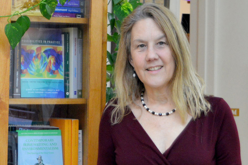 Closeup of Potts standing next to book case.