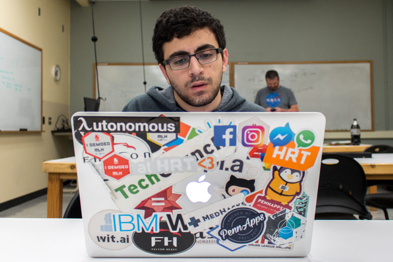 Khorram sits at laptop computer covered with stickers.