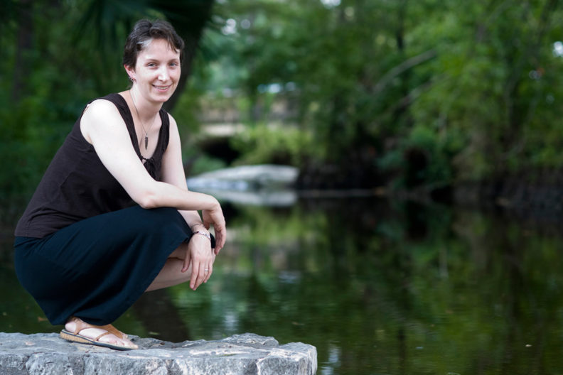 Moffett kneeling on a rock next to a stream.