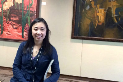 Zhang standing in front of large paintings.