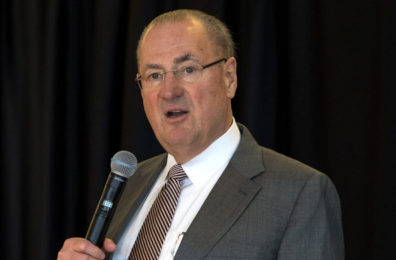 Closeup of Schweitzer speaking with microphone on stage.