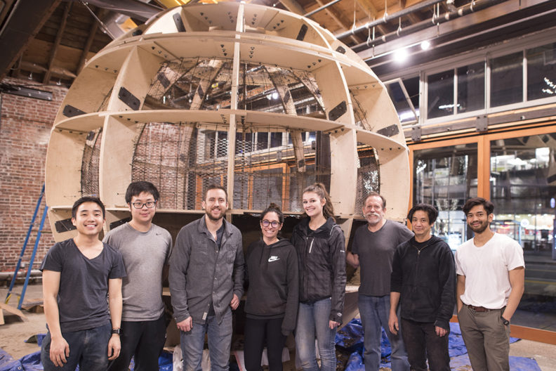 Members of the WSU Circum-ambience project team in front of a globe-shaped, wood-frame structure.