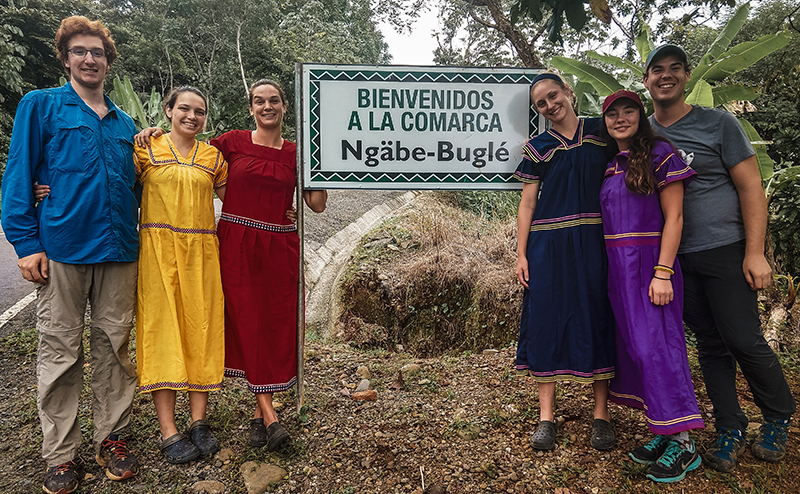 People standing beside sign reading 'Bienvenidos a la Comarca Ngabe-Bugle'.