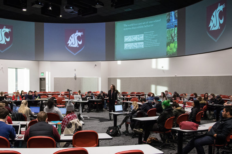 Whitman lecturing to a classroom of students in a state of the art videoconferencing facility.