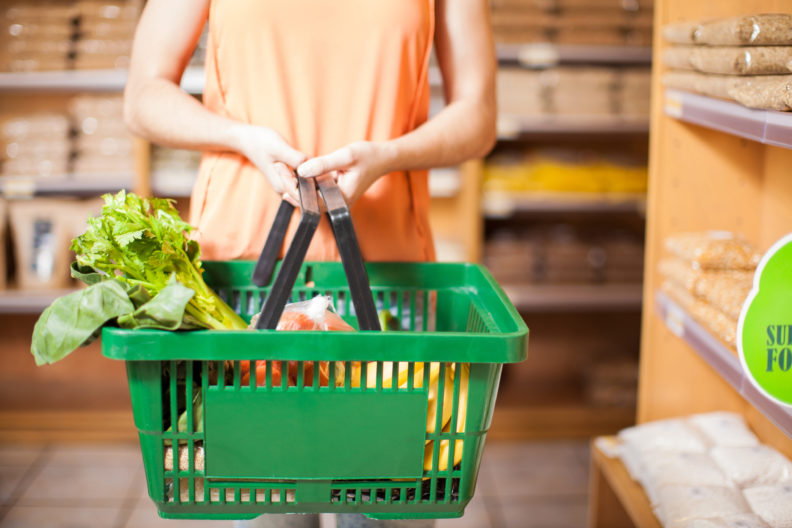 Closeup of woman holding basket full of groceries.