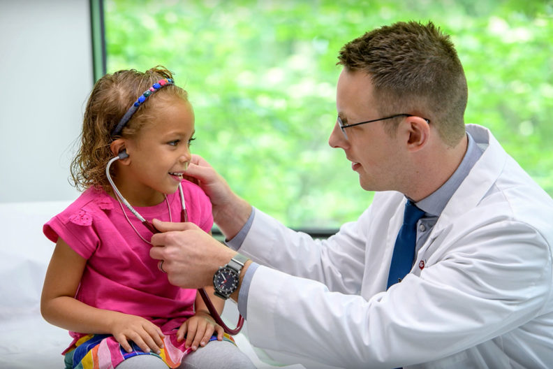 WSU medical student letting young girl listen while using his stethoscope.