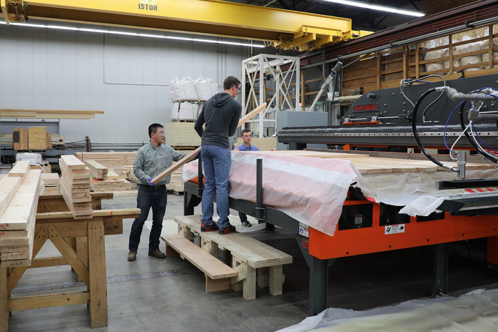 Researchers feeding lumbar materials through CLT manufacturing system.