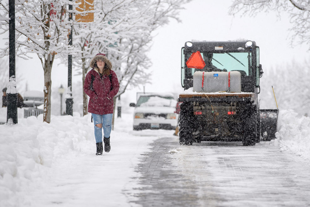 student shares WSU Pullman sidewal with truc and other large snow removal equipment