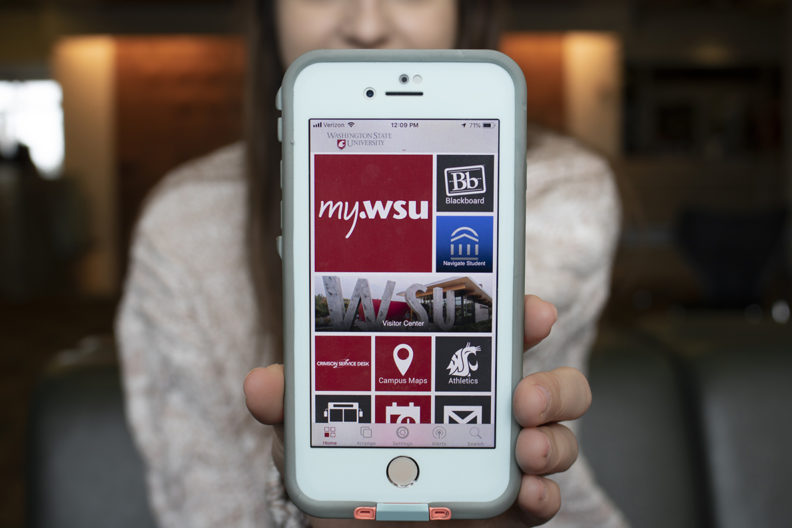 Woman shows smart phone with myWSU app open.