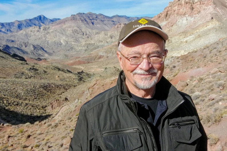 Jacoby standing amongst sagebrush with a mountain range in the distance.
