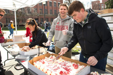 Students serving cake during WSU's 128th birthday.