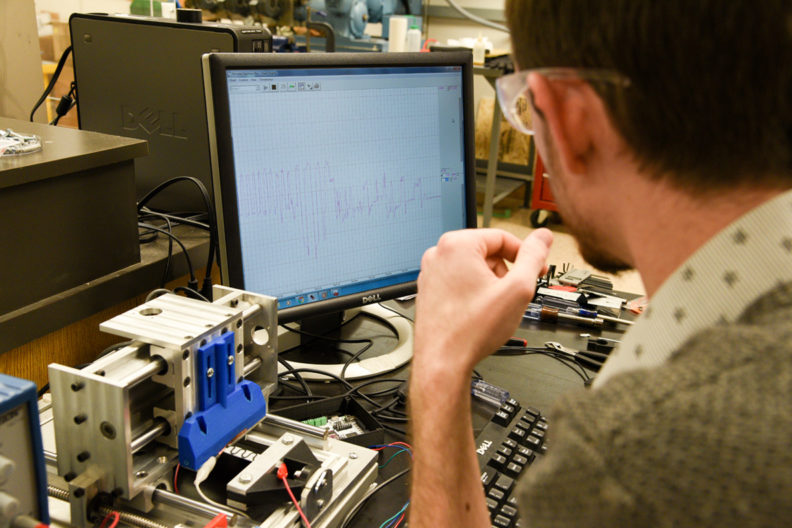 Engineer looking at a computer and 3D printer.
