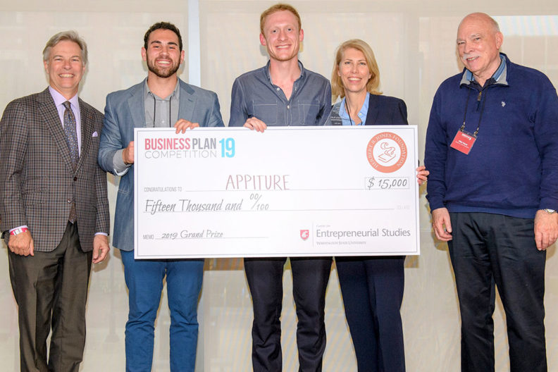 Appiture team members holding a giant check as they stand alongside dean and directors associated with the event.