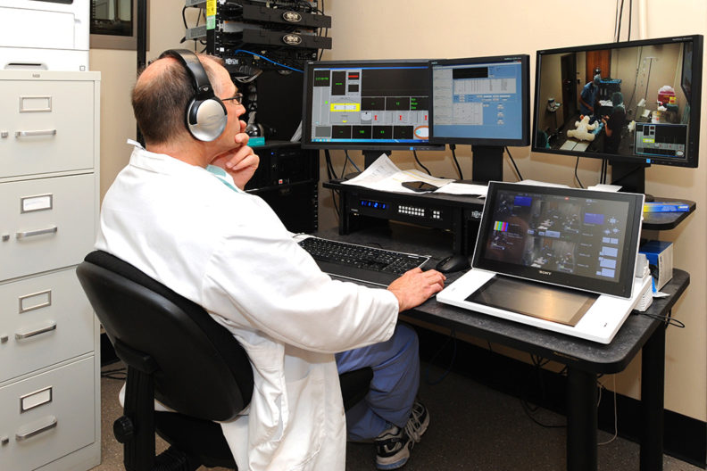 Dr. Robert Keegan closely watching veterinary students on multiple computer monitors.