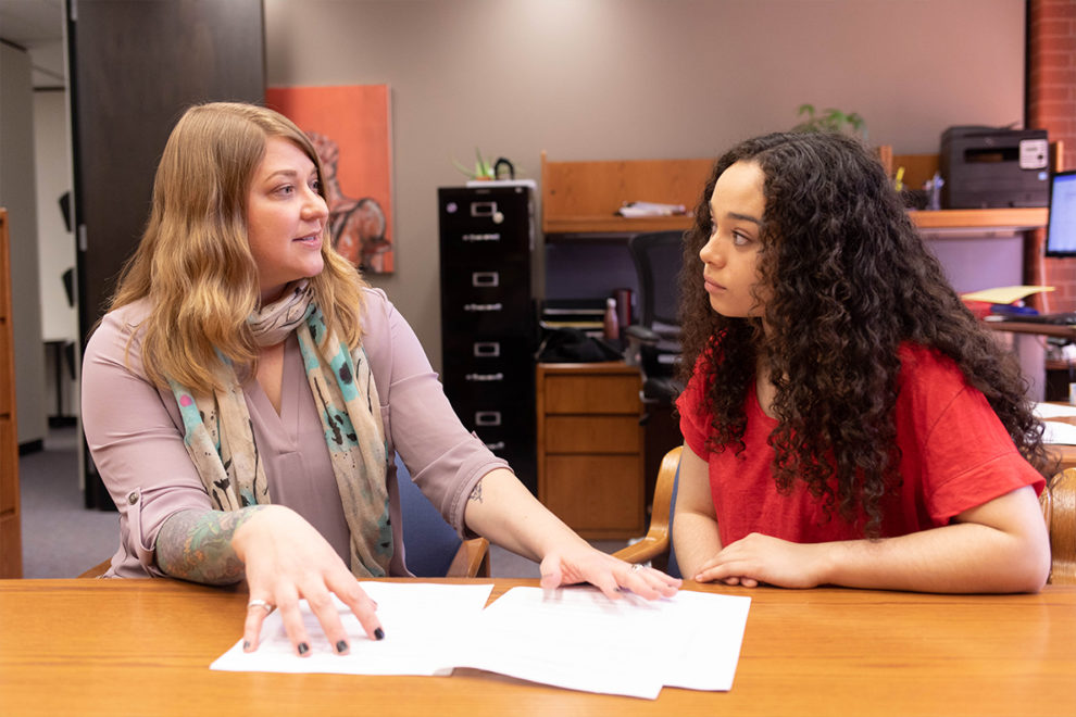 Holly Ashkannejhad and Jhordin Prescott sit next to each other at a table discussing plans to improve Executive Policy #15.