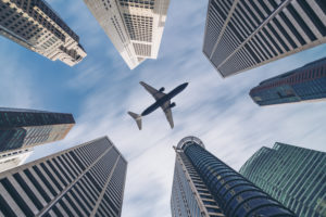 Airplane flying over city buildings, high-rise business skyscrapers. 