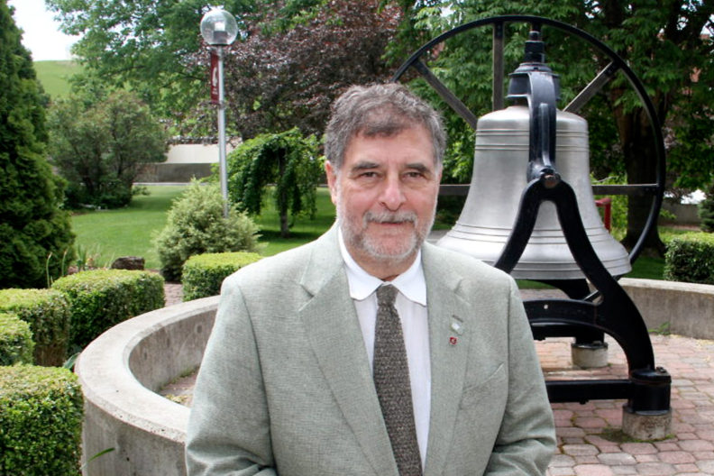 Closeup of Richard Zack in front of the WSUAA victory bell.