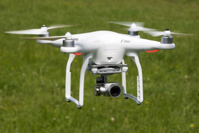 Drone with mounted camera hovering over a field.