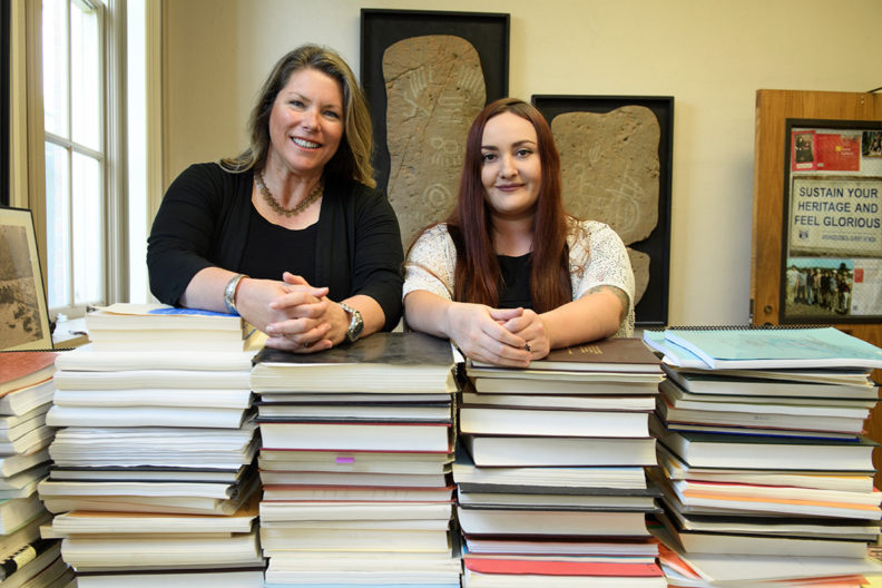 Tushingham and Fulkerson stand behind a large stack of books.
