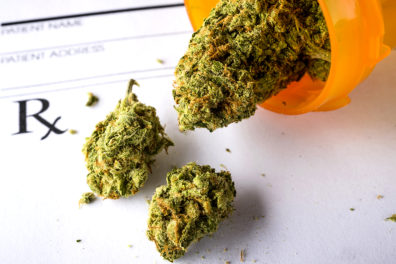 An open prescription bottle with medicinal marijuana and a blank prescription slip.