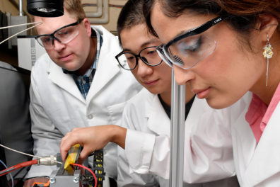 Three scientists looking at a work table.
