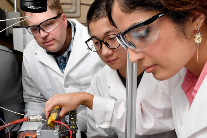 Three scientists looking at a work table