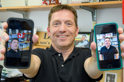 Closeup of Chris Barry holding two phones.