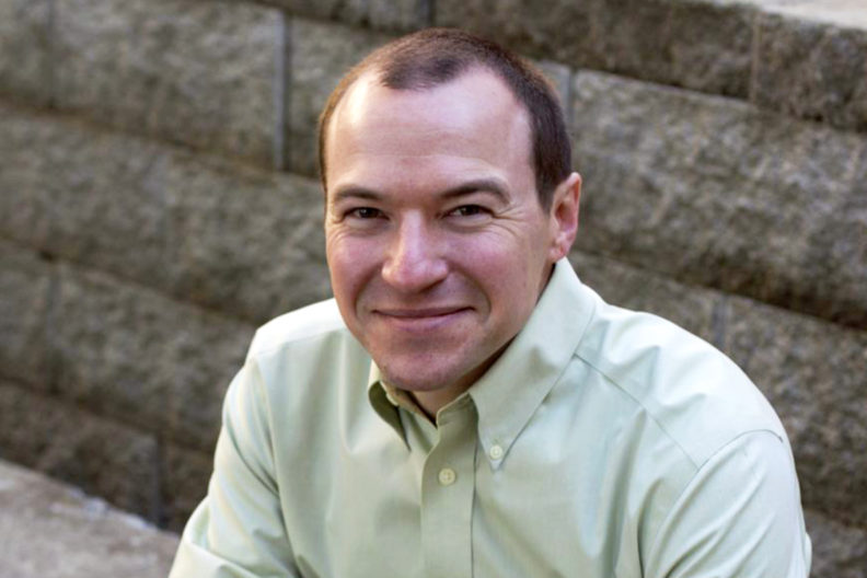 Closeup of Brian French sitting on a concrete bench.