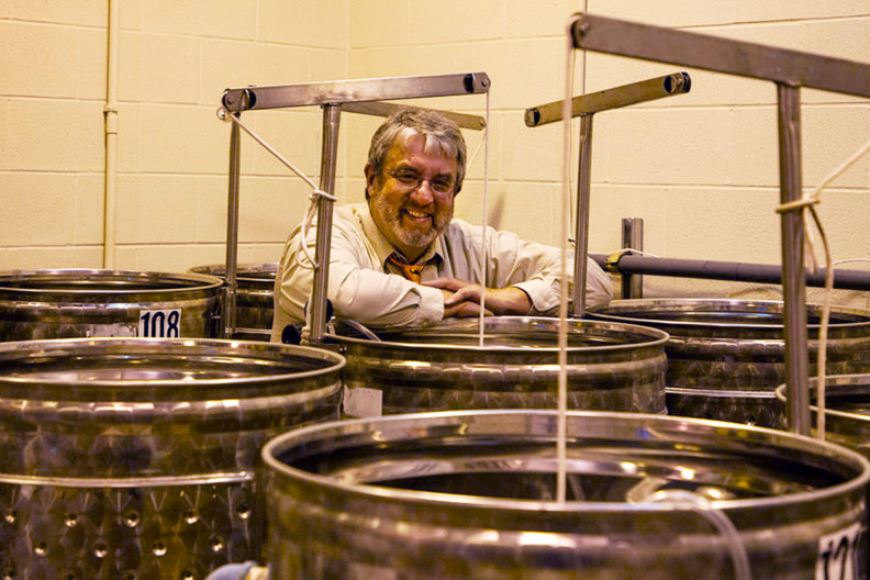 Charles Edwards standing behind a row of large metal containers.