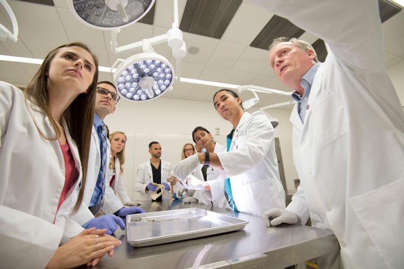 Medical students stand around a surgical table.