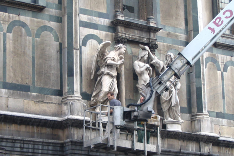 Professor Matthew Cohen works from scaffolding on a building.